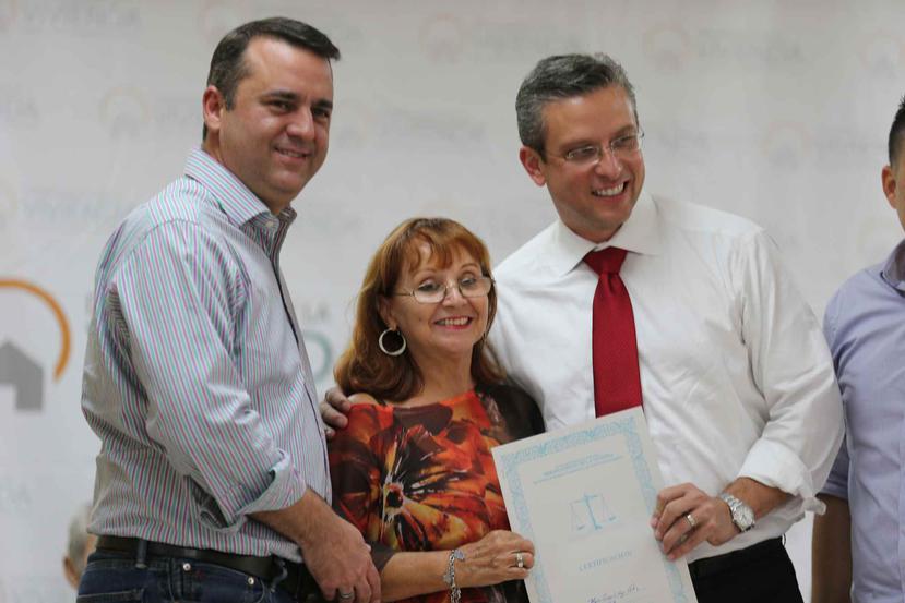 El secretario de la Vivienda, Alberto Lastra, entrega el título de propiedad a María Concepción Ortiz junto al gobernador.