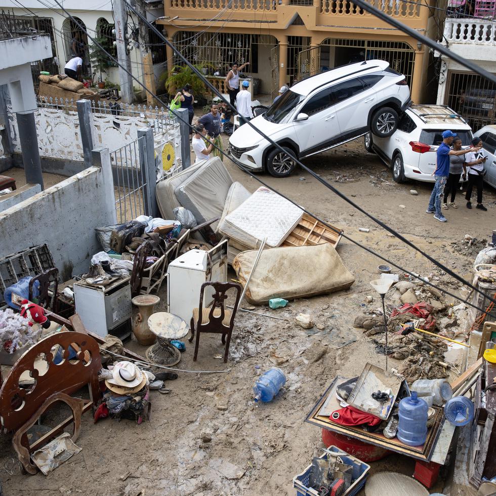 SANTO DOMINGO (REPÚBLICA DOMINICANA), 19/11/2023.- Personas quitan el lodo de sus muebles, junto a varios vehículos que fueron arrastrados por la corriente, hoy en Santo Domingo (República Dominicana). Las lluvias torrenciales que afectan a República Dominicana desde el viernes han obligado a desplazar de sus hogares a cerca de 8.000 personas, dañado viviendas e infraestructuras y más de una docena de muertos, aunque las autoridades solo confirmaron nueve fallecidos. EFE/Orlando Barría
