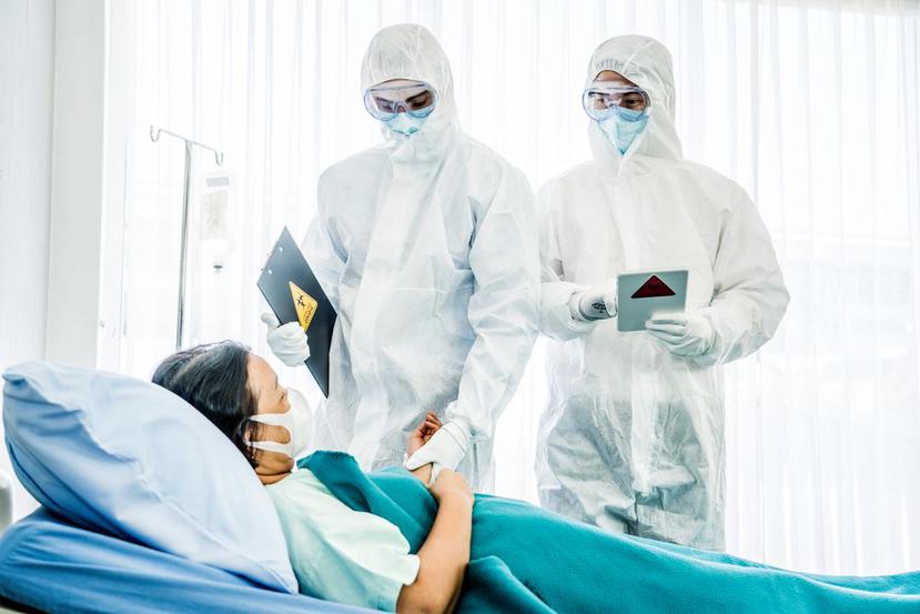 Un par de médicos se cubren para evitar el contagio de una paciente con coronavirus. (Shutterstock)