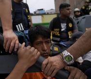 Un manifestante antigubernamental detenido se sienta en la parte trasera de una camioneta de la policía en la Universidad de San Marcos en Lima, Perú, el sábado 21 de enero de 2023.