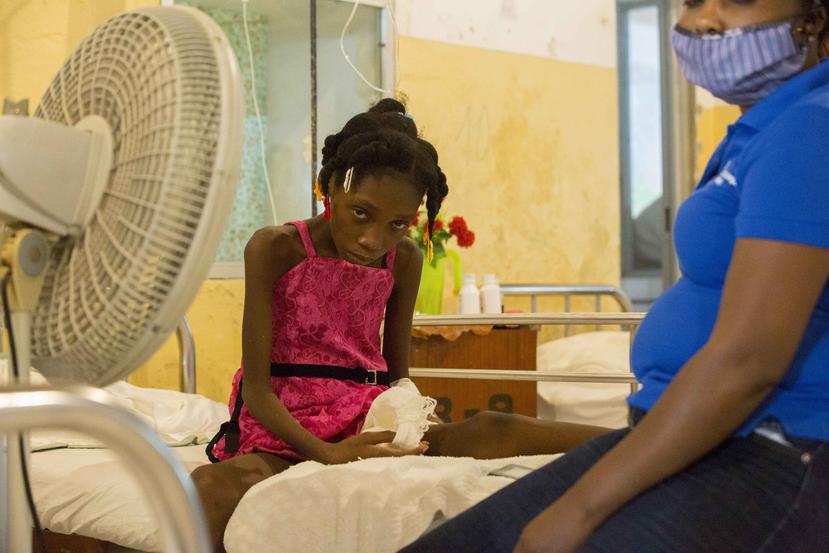Amazon Annegardine, de 11 años, que recibe tratamiento por niveles anómalos de azúcar en sangre, se sienta en una cama junto a su madre en el Hospital de la Inmaculada Concepción, en Les Cayes, Haití.