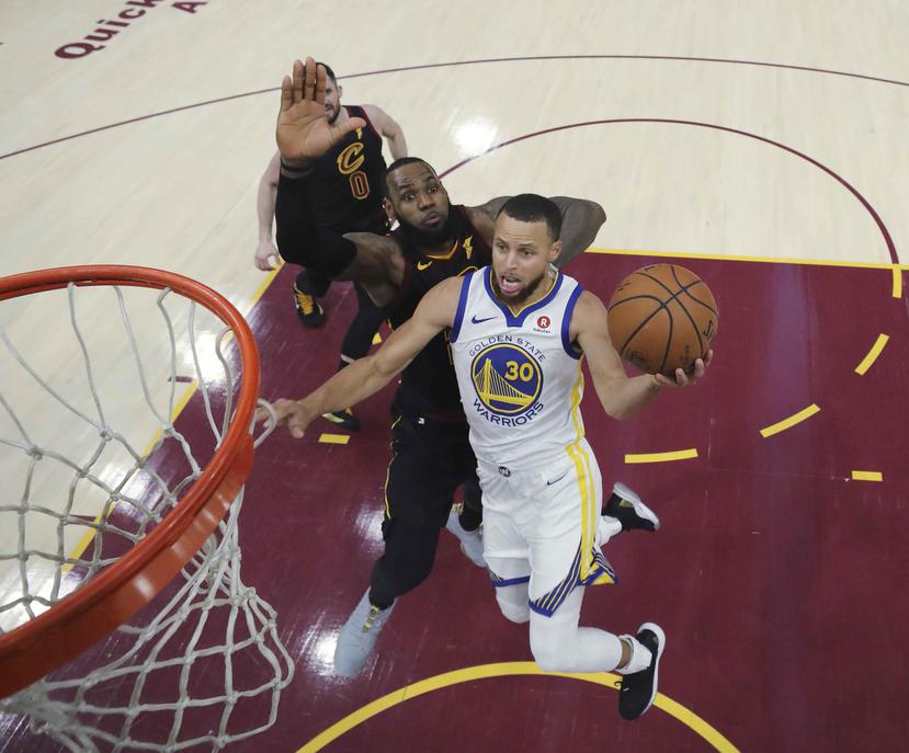 LeBron James, de los Cavaliers de Cleveland, intenta evitar que Stephen Curry, de los Warriors de Golden State, enceste. (AP)