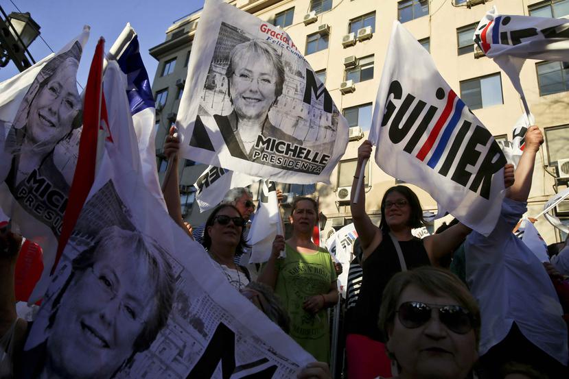 Simpatizantes del candidato oficialista Alejandro Guillier, de Nueva Mayoría, ondean banderas con el rostro de la actual presidenta, Michelle Bachelet, durante el cierre de campaña de Guillier en Santiago. (AP)