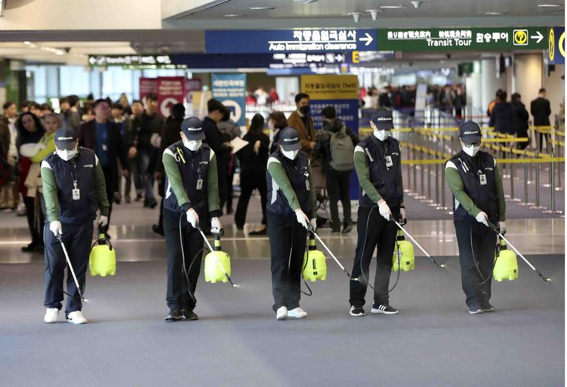 Trabajadores rocían una solución antiséptica en el salón de arribos del Aeropuerto Internacional de Incheon, Corea del Sur, martes 21 de enero de 2020. (Suh Myung-geon/Yonhap via AP)