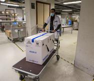 Un trabajador de la salud traslada parte de un embarque de la vacuna de Pfizer y BioNTech contra el COVID-19 en el hospital UZ Leuven en Lovaina, Bélgica.