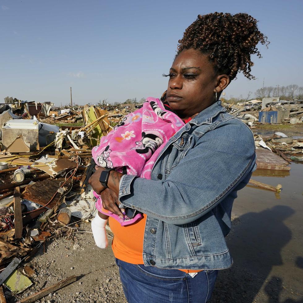 Wonder Bolden carga a su nieta de un año, Journey Bolden, junto a los restos de la casa rodante de su madre, demolida por un tornado, el sábado 25 de marzo de 2023, en Rolling Fork, Mississippi. (AP Foto/Rogelio V. Solis)