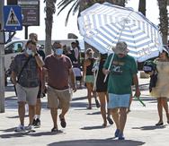 Un hombre se protege del intenso calor con una sombrilla de playa por las calles de la ciudad de Alicante, España.