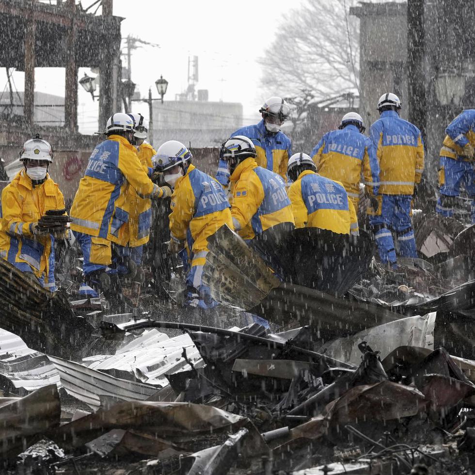 Cae la lluvia mientras agentes de policía retiran escombros tras un incendio en un mercado en Wajima, prefectura de Ishikawa, Japón, el 6 de enero de 2024.