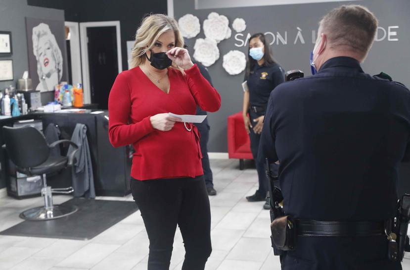 Shelley Luther habla con un oficial de policía de Dallas después de que fue citada por reabrir su salón ‘A la Mode’ en Dallas. (AP)
