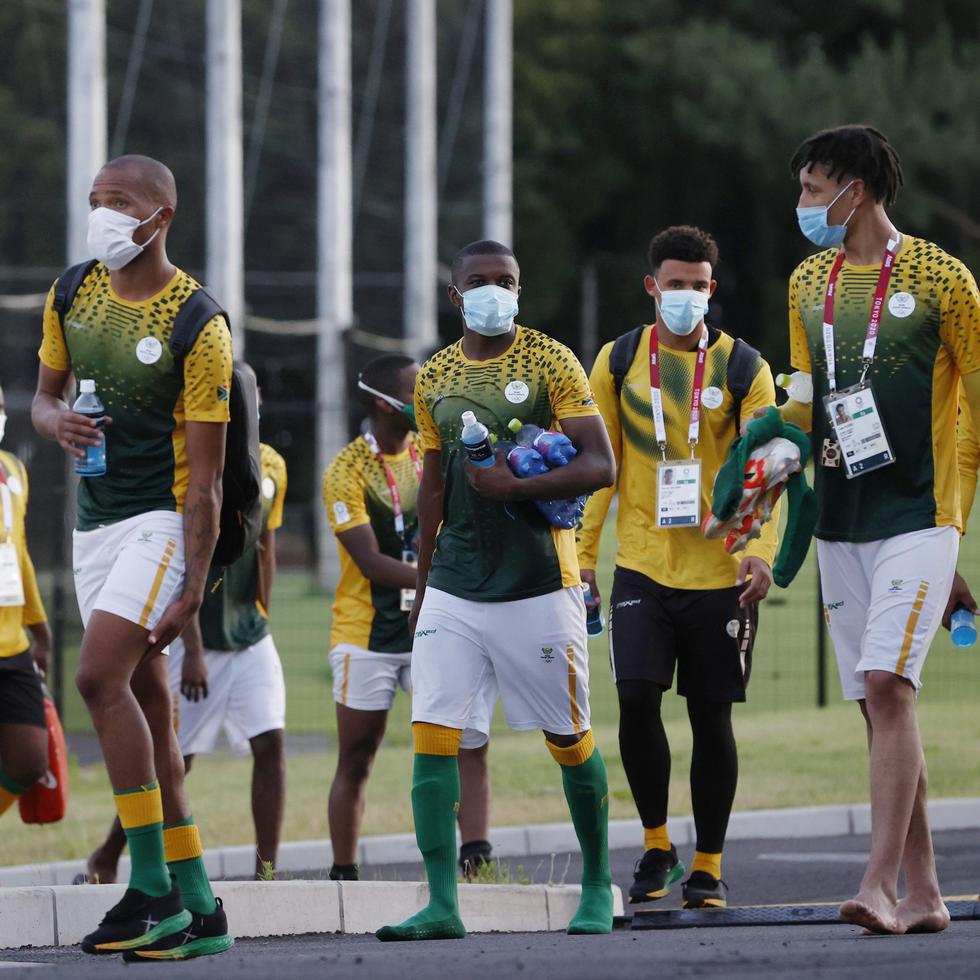 El equipo de fútbol de Sudáfrica, todos con mascarillas, salen de su entrenamiento en Chiba, a una hora de Tokio.