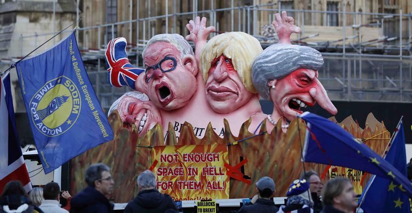Manifestantes en contra del Brexit frente a un vehículo decorado con retratos de los principales políticos británicos, de derecha a izquierda la premier Theresa May, Boris Johnson, Michael Gove, David Davis, fuera del Palacio de Westminster el jueves 14 d