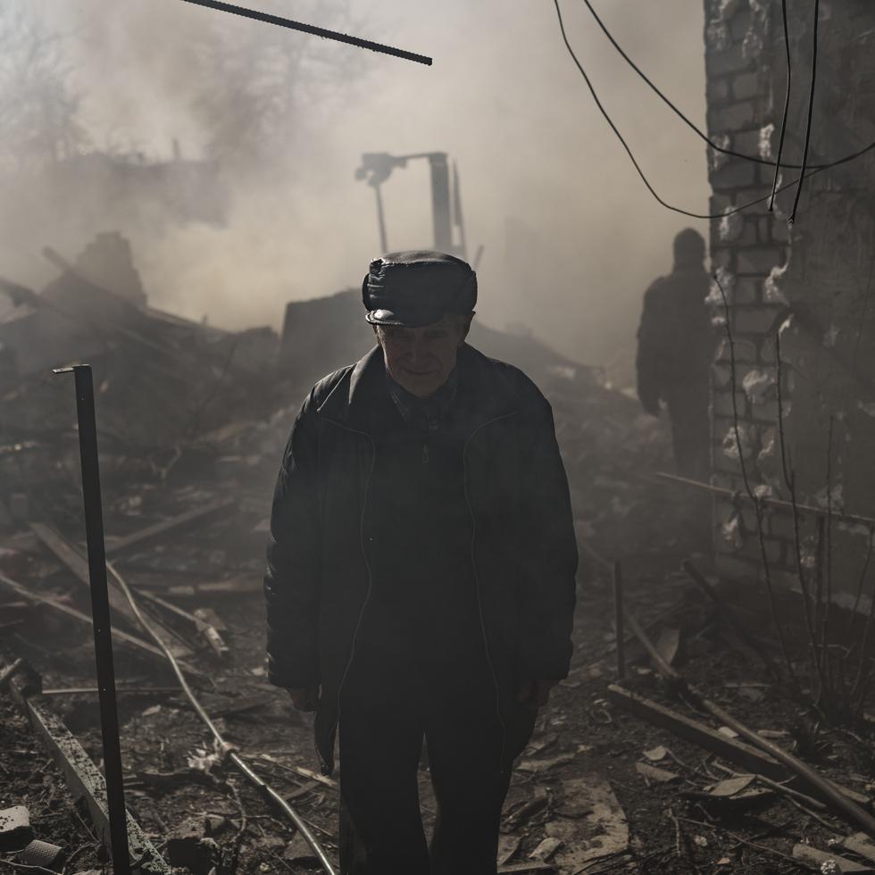 A man walks amid smoke from a burning house, destroyed after a Russian attack in Kharkiv, Ukraine, Thursday, March 24, 2022. (AP Photo/Felipe Dana)