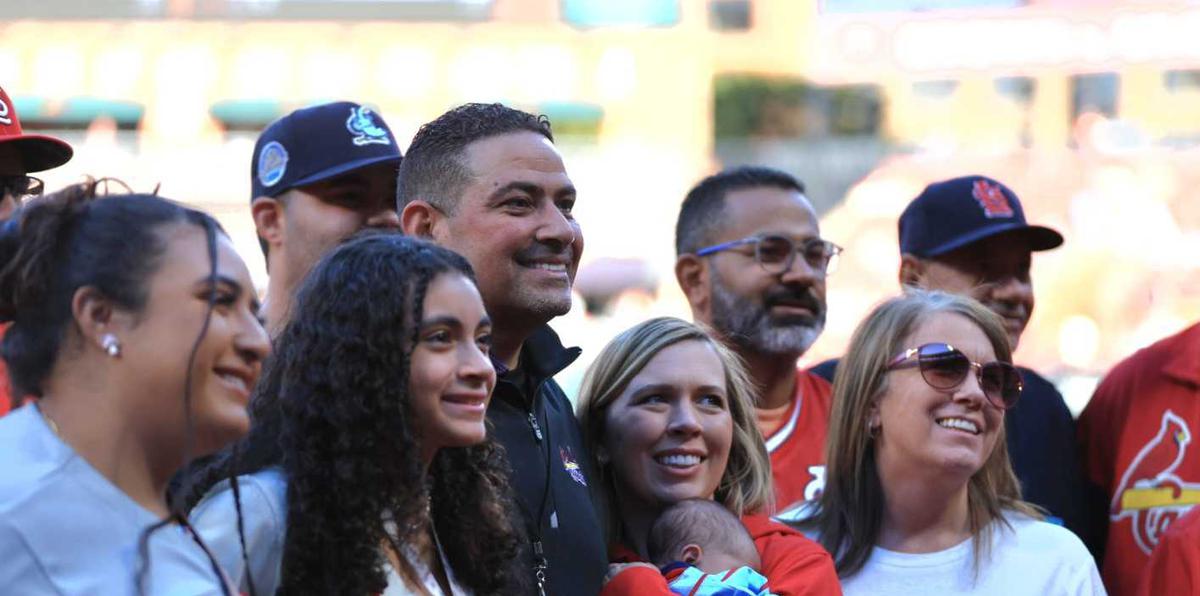 Familiares de Yadier Molina, incluyendo a su hermano mayor Bengie Molina (al centro con camisa oscura), posan para una foto en el terreno de juego del Busch Stadium.