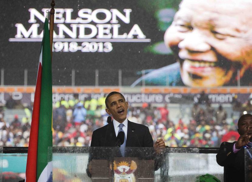 Esta foto de archivo del martes 10 de diciembre del 2013 muestra al expresidente estadounidense Barack Obama hablando durante las exequias del expresidente sudafricano Nelson Mandela, al fondo, en Soweto, Johannesburgo. (AP)