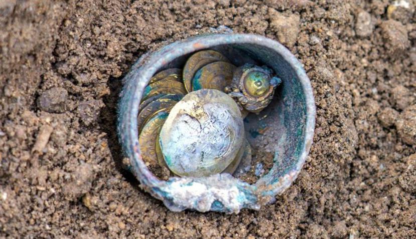 Fotografía facilitada por la Autoridad Israelí de Antigüedades, que muestra las monedas y el pendiente encontrados en el puerto de Cesárea, en Israel. (EFE)