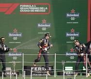 El británico Lewis Hamilton, izquierda, de Mercedes; el holandés Max Verstappen, centro, de Red Bull; y el mexicano Sergio Pérez, de Red Bull, festejan en el podio después del Gran Premio de México de la Fórmula Uno.