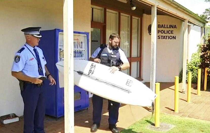 Imagen tomada de un vídeo en donde un policía muestra la tabla de surf de la víctima en una estación policial en Ballina, Australia. (Australian Broadcasting Corporation vía AP)