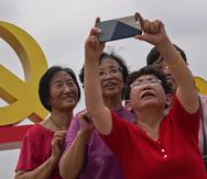 Women take a selfie with a communist party's logo on display at Tiananmen Square to mark the 100th anniversary of the founding of the ruling Chinese Communist Party in Beijing on Monday, July 5, 2021. Chinese leader Xi Jinping on Tuesday attacked calls from some in the U.S. and its allies to limit their dependency on Chinese suppliers and block the sharing of technologies. (AP Photo/Andy Wong)