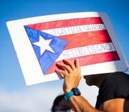 Pancarta con la bandera de Puerto Rico y el mensaje: "Justicia salarial. Retiro digno".