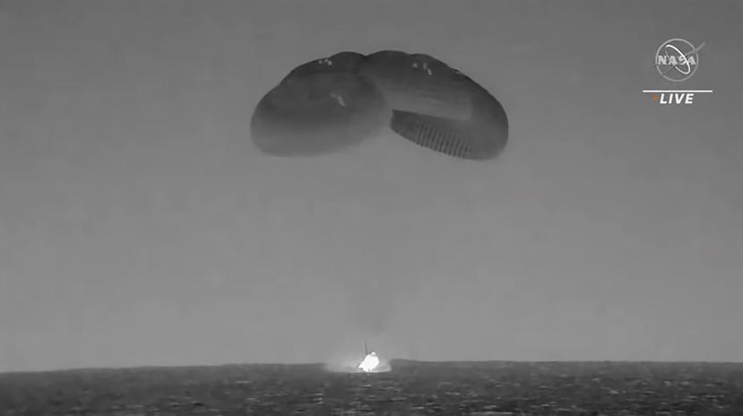 En esta imagen tomada de un video divulgado por la NASA, una cápsula de SpaceX --con paracaídas desplegados para disminuir su velocidad-- cae en el Océano Atlántico el lunes 4 de septiembre de 2023, frente a la costa de Florida.