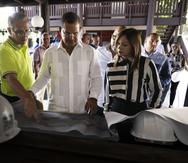 El alcalde de Coamo, Juan Carlos García Padilla (camisa verde), le muestra los planos de la hospedería de Los Baños al gobernador Pedro Pierluisi.