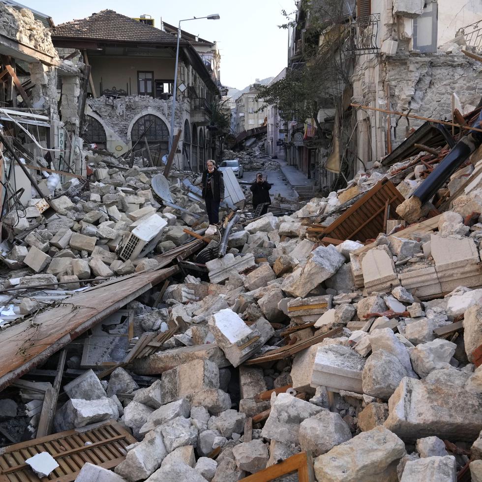 Una mujer turca sobre los escombros de las casas patrimoniales que se destruyeron durante el devastador terremoto, en la antigua ciudad de Antakya, en el sur de Turquía, el lunes 13 de febrero de 2023.