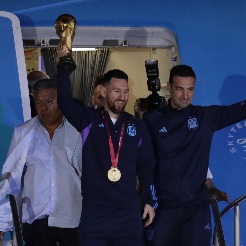 Lionel Messi de la selección argentina de fútbol saluda con el trofeo del Mundial de Fútbol Catar 2022 junto al seleccionador Lionel Scaloni a su llegada hoy, al Aeropuerto Internacional de Ezeiza a unos 22km de Buenos Aires (Argentina). EFE/ Raúl Martínez