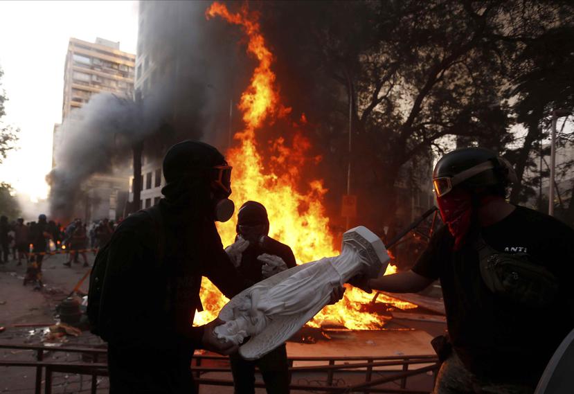 Manifestantes antigubernamentales arrojan al fuego artículos religiosos capturados en una iglesia de la policía chilena durante una protesta en Santiago, Chile. (AP/Luis Hidalgo)