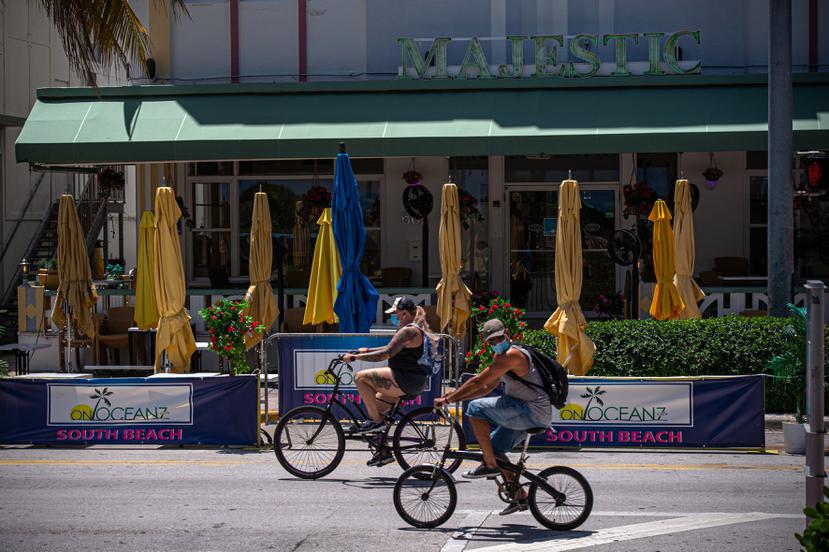 Dos personas pasan en bicicleta frente al hotel Majestic en South Beach, en Miami.