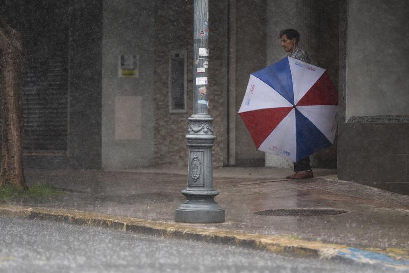 Imagen de archivo de un hombre que busca resguardo de una lluvia en el área metropolitana.