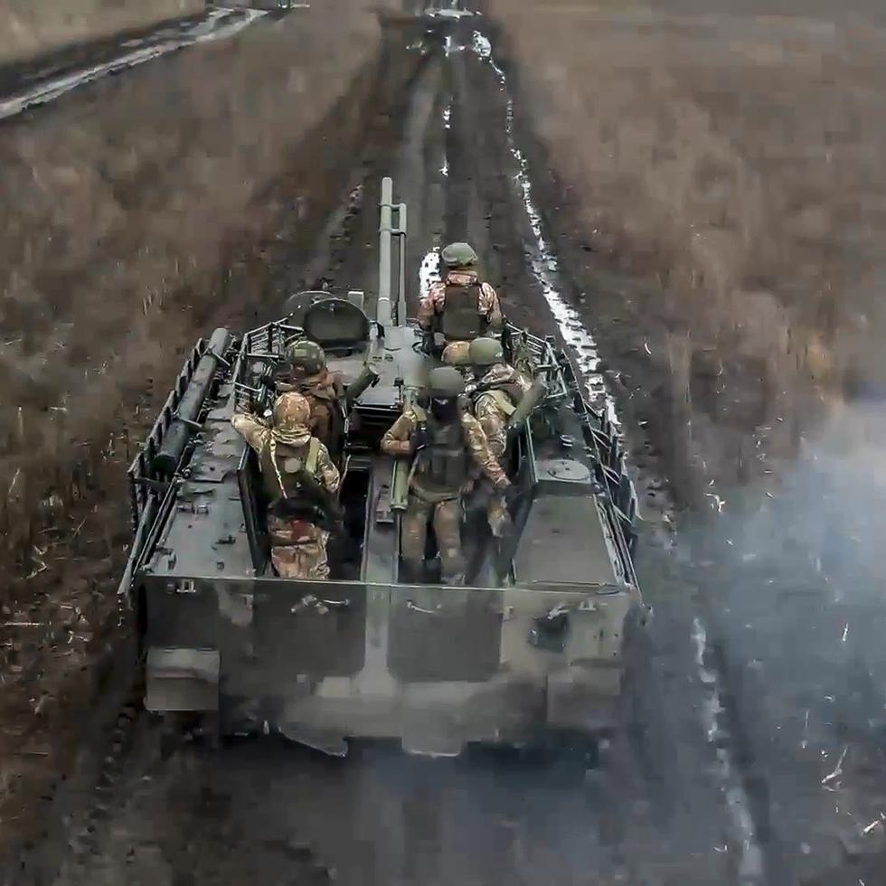Soldados rusos avanzan en un vehículo blindado para tomar posiciones y disparar contra blancos enemigos, en un lugar no identificado de Ucrania.