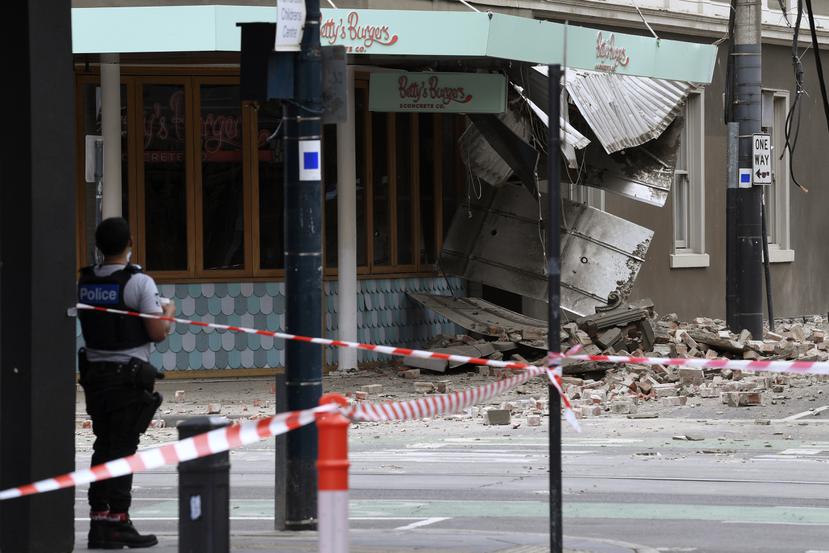 Un agente de policía cierra una intersección donde cayeron escombros sobre la calle después de un sismo en Melbourne, Australia.
