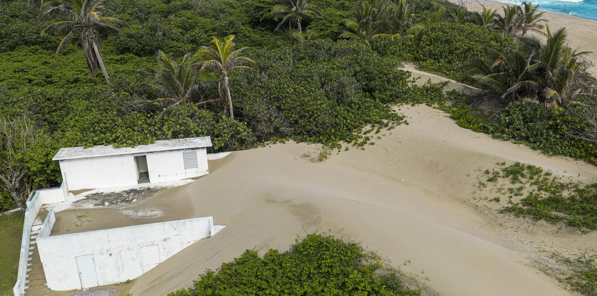 Fotografía aérea de impacto de la acumulación de arena sobre una residencia en la playa Hallows del barrio Islote en Arecibo.