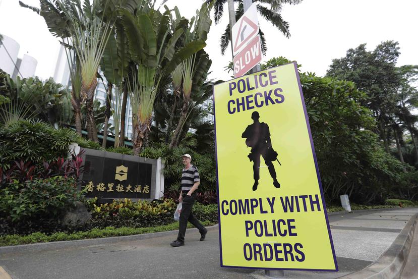 Un hombre pasa al lado de un cartel policial en la entrada que va hacia el hotel Shangri-la. (AP)