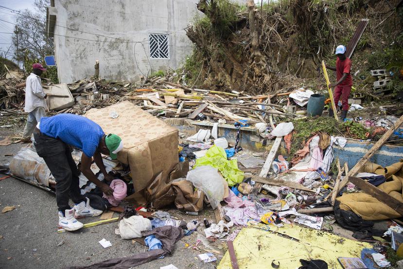 Hombres recogen objetos entre los restos de una casa que resultó completamente destruida durante el paso del huracán Fiona en República Dominicana.