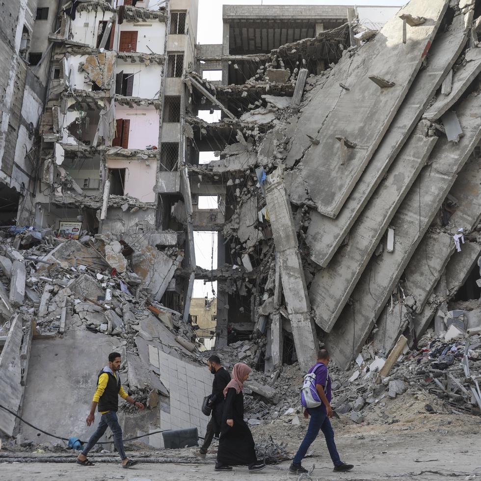 Palestinos caminan entre edificios impactados por ataques en Gaza.