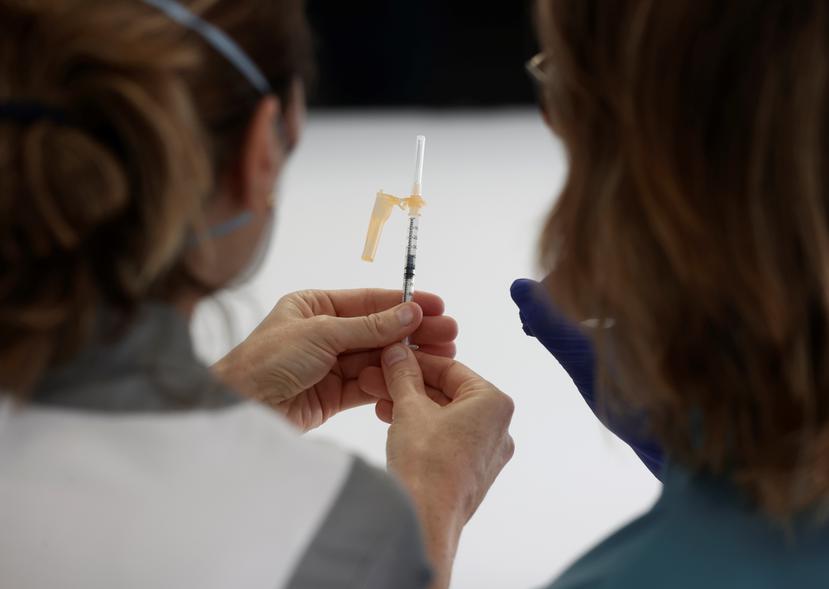 Dos enfermeras observan una dosis de vacuna contra el COVID-19.