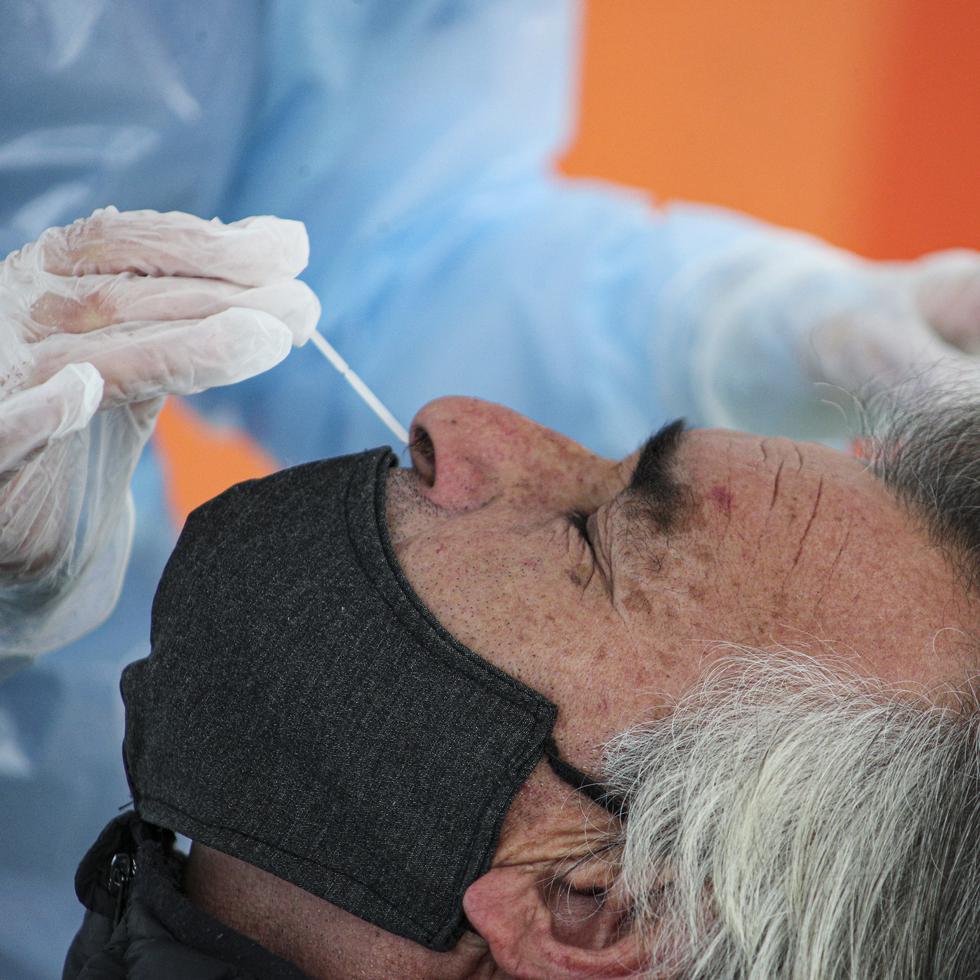 A healthcare worker takes a nasal swab sample from a merchant at a new coronavirus testing site geared at street vendors, at a sports center in the Puente Alto neighborhood of Santiago, Chile, Friday, July 10, 2020. (AP Photo/Esteban Felix)