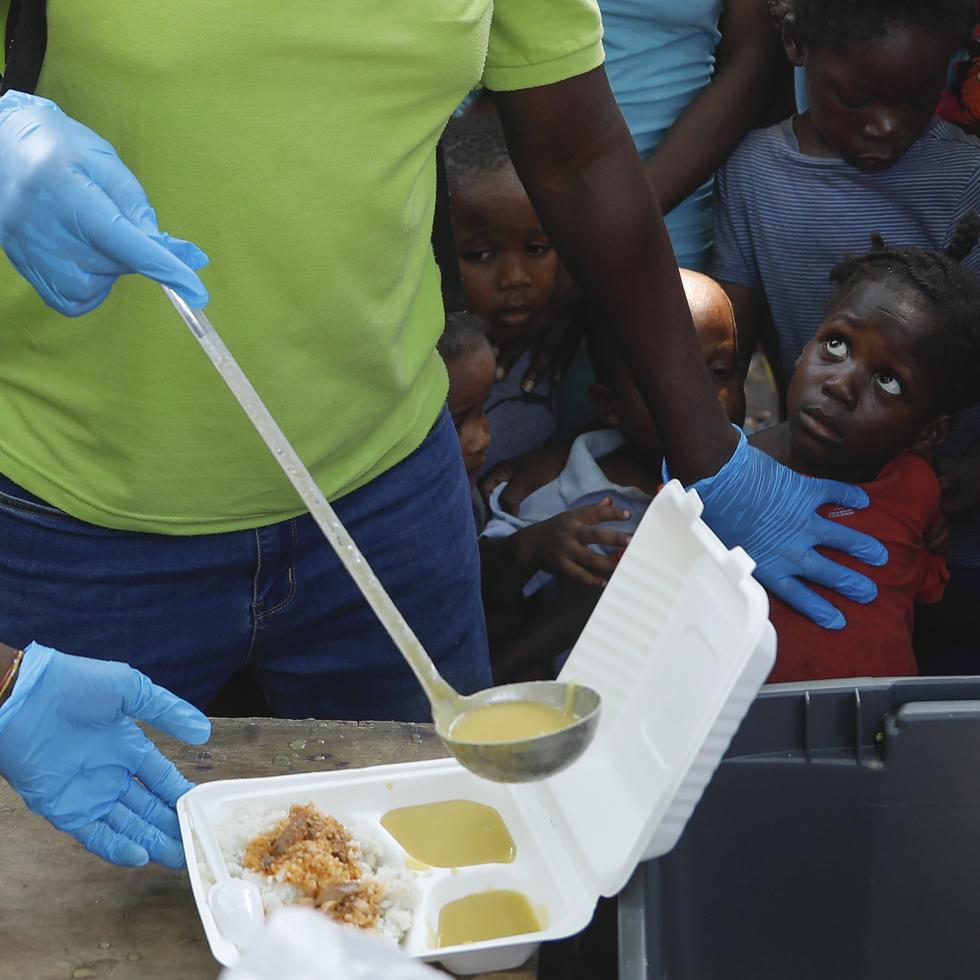Una persona sirve sopa en un recipiente mientras varios niños hacen fila para recibir comida en un albergue para familias desplazadas por la violencia de las pandillas, en Puerto Príncipe, Haití. (AP / Odelyn Joseph)