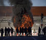 Trabajadores portuarios de pie ante una barricada en llamas junto al puerto de Marsella, en el sur de Francia, el miércoles 22 de marzo de 2023.