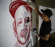El artista Julián Castillo pinta un retrato del cantante puertorriqueño René Pérez, Residente, con sangre humana, en el barrio Siloé, en Cali, Colombia.