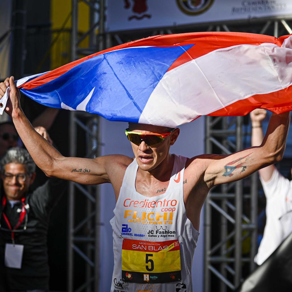 El orocoveño Alexander Torres celebra con una bandera de Puerto Rico tras cruzar la meta.