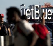 Viajeros pasan junto a un cartel de JetBlue antes del fin de semana feriado del 4 de julio en el aeropuerto John F. Kennedy.