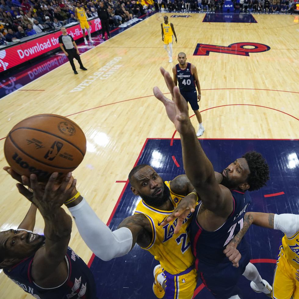 LeBron James (centro), de los Lakers de Los Ángeles, se alza para intentar un tiro entre De'Anthony Melton, izquierda, y Joel Embiid, de los 76ers de Filadelfia, durante la segunda mitad del partido del lunes.