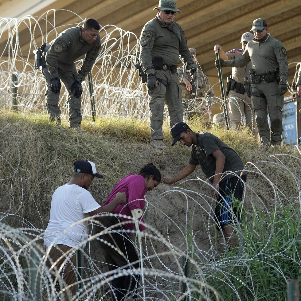 Soldados y guardias de Texas ayudan a una inmigrante que quedó atrapada en un alambre de púas después de cruzar el Río Grande desde México hacia Estados Unidos.