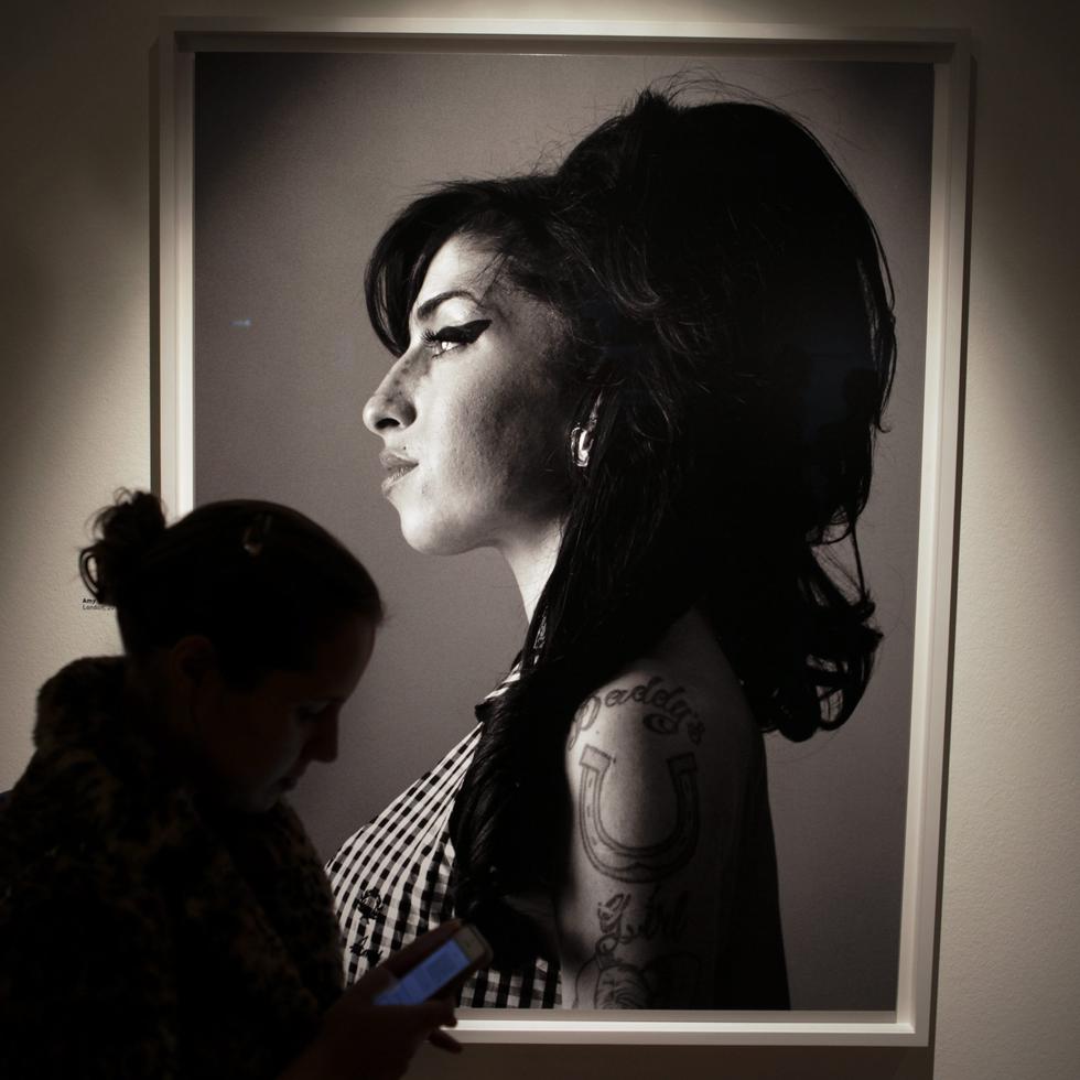 Un visitante pasa frente a un retrato de la fallecida cantante británica Amy Winehouse hecho por el cantante y compositor canadiense Bryan Adams.