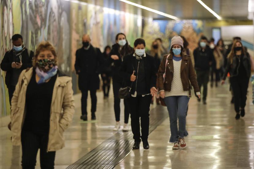 Las personas usan máscaras para evitar la propagación del COVID-19 mientras caminan en el metro de la estación de tren Garibaldi, en Milán, Italia, el martes 13 de octubre de 2020.