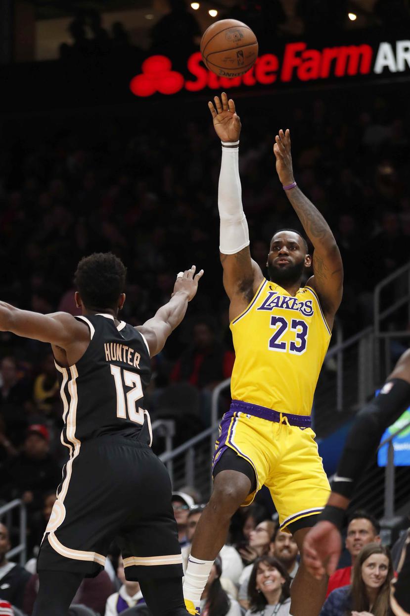 LeBron James, de los Lakers de Los Ángeles, realiza un disparo al canasto ante la defensa de De'Andre Hunter, de los Hawks de Atlanta. (AP / John Bazemore)