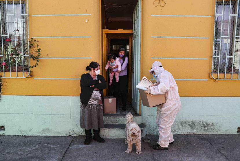 Un trabajador del gobierno de Chile entrega una caja de comida a ciudadanos. (AP)