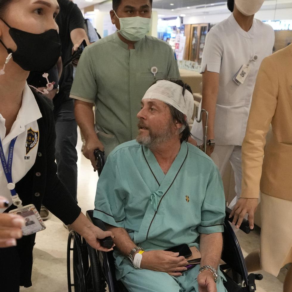 Un pasajero australiano, en el centro, que resultó herido en un vuelo afectado por turbulencias, habla con periodistas en el hospital Samitivej Srinakarin en Bangkok, Tailandia, el jueves.